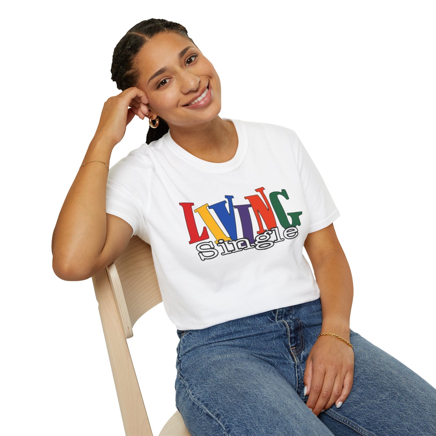 Person wearing a white t-shirt with colorful text "living single" sitting on a chair.